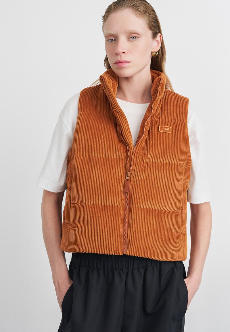 Puumähibest burnt orange värviga, kõrge kraega, tõmblukuga ja kvaliteetse tekstuuriga. Omab logot ja küljetaskuid. Kandmine valge särk üle.