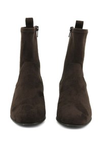 Stivali ankle in suede marrone con un design elegante, dotati di zip laterali e una texture liscia. Il tacco è basso e arrotondato per garantire stabilità.