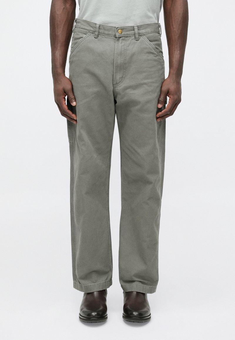 Γκρι βαμβακερό παντελόνι με ίσια γραμμή, διαθέτε�ι κούμπωμα με κουμπί, μπροστινές τσέπες και διακριτική υφή. Φορεμένο με σκούρα παπούτσια.