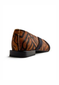 Scarpa flat con stampa animalier in marrone e nero, dotata di tomaia in pelliccia testurizzata, tacco nero solido e design elegante con hardware ridotto al minimo.