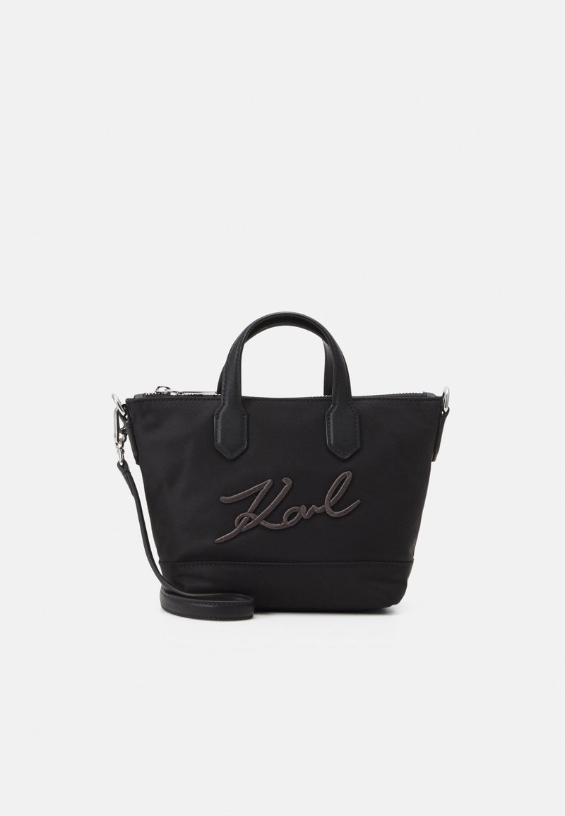 Czarna torebka nylonowa z skórzanymi akcentami, górnymi uchwytami i odczepianym paskiem na ramię. Przednia strona zdobiona haftowanym logo "Karl".