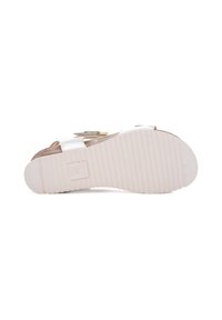 White sandal featuring a flat rubber sole with ridges, adjustable buckle strap, and a textured insole with a light color finish.