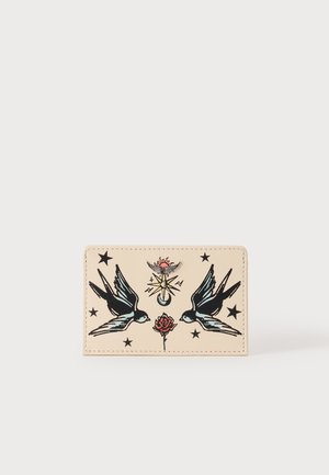 Crème kleurige kaarthouder met zwarte, blauwe en rode tattoo-stijlontwerpen van twee zwaluwen, een roos, sterren en een hemels symbool met een zon en maan.