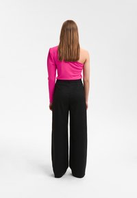 Enganliegendes, langärmeliges pinkes Oberteil mit einem freien Schulter, kombiniert mit hochtaillierten, schwarzen, weiten Hosen; glatte Textur, modernes Design.