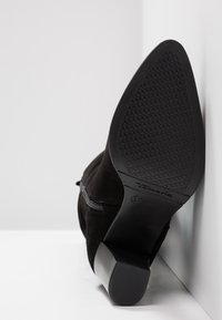 Bottine en daim noir avec bout pointu, talon bloc, fermeture éclair latérale et semelle texturée, taille 37 marquée.