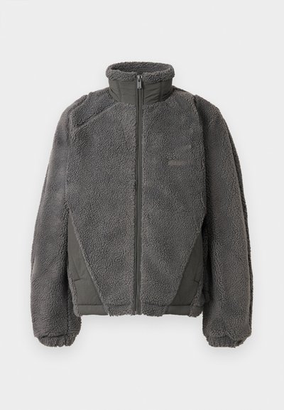 Hallja hall villane jakk kõrge kaelusega, ees lukuga ja tekstuurse välimise kangaga. Omab kontrastset tumeda halli paneeli külgedel.