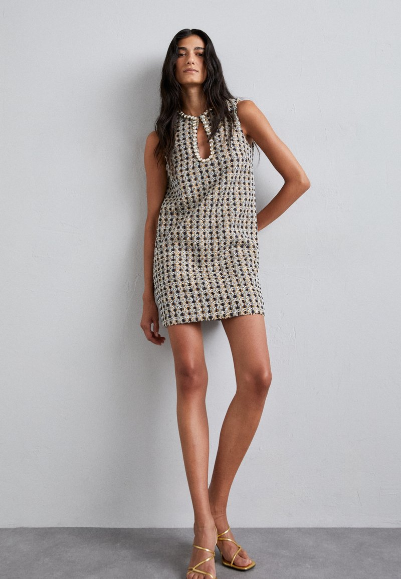 Kurzärmeliges, gemustertes Kleid mit einem Ausschnitt im Schlüsselbundstil, in Schwarz, Creme und Goldtönen. Bietet eine figurbetonte Form und strukturierter Stoff.