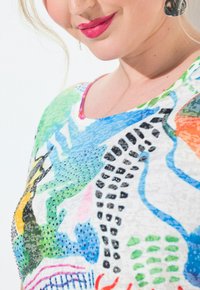 Farbenfrohes gemustertes Oberteil mit kurzen Ärmeln, das abstrakte Designs in Blau, Grün, Orange und Schwarz zeigt, verziert mit Strasssteinen.