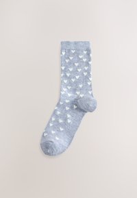 Chaussette bleu clair en matière douce, présentant un motif de petits cœurs blancs, avec un bord-côte et un design à bout arrondi.