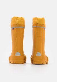 Bottes en caoutchouc imperméables jaunes avec une finition texturée, présentant une bande réfléchissante et un accent circulaire en argent au niveau du talon.