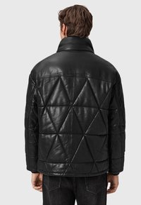 Sort læderjakke med et geometrisk quiltet mønster, der har en høj krave og afslappet pasform. Glat tekstur og enkelt design.