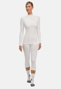 Maglia a maniche lunghe bianca di base e pantaloni capri aderenti, realizzati in materiale liscio e leggero con un design aderente e dettagli di cucitura sottili.