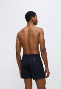 Μπλε ναυτικού χρώματος μαγιό βερμούδα με ελαστική μέση και τσέπη στο πίσω μέρος με μικρό λογότυπο. Ομαλό ύφασμα και μήκος πάνω από το γόνατο.