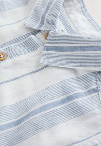 Collared shirt with light blue and white horizontal stripes and light brown buttons, showing the collar and upper chest area.