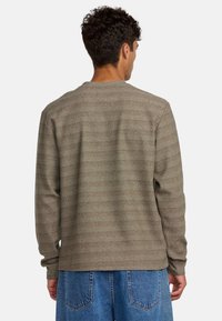 Braun gestreiftes Langarmshirt mit Rundhalsausschnitt, aus einem strukturierten Stoff gefertigt. Das Shirt verfügt über gerippte Bündchen und einen geraden Saum.