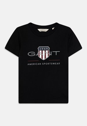Schwarzes T-Shirt mit kurzen Ärmeln aus Baumwolle, mit einem Schild-Logo mit roten Streifen, dem Wort "GANT" und "AMERICAN SPORTSWEAR" darunter.