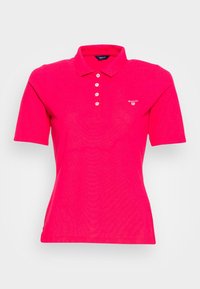 Polo tričko v jasně růžové barvě z bavlny, s klasickým límcem, tříknoflíkovou légou a malým vyšitým logem na prsou.