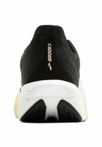 Zapatilla de correr negra con parte superior de punto, descansando sobre una entresuela blanca y una suela negra texturizada. Presenta la marca "Brooks" en el talón.