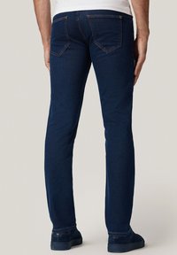 Ciemnoniebieskie dżinsy w prostym kroju, z kontrastującymi pomarańczowymi szwami oraz dwoma tylnymi kieszeniami z subtelnym wzorem ściegów.