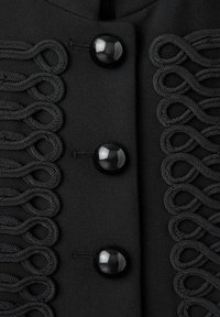 Tissu noir avec trois boutons noirs brillants au centre et des boucles tressées décoratives disposées symétriquement de chaque côté des boutons.