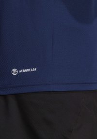 Nachtblaues, feuchtigkeitsabweisendes Shirt mit einem strukturierten Muster. Mit "AEROREADY"-Logo in Weiß in der unteren linken Ecke.