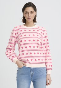 Pull-over rose clair avec des rayures horizontales et petits motifs en forme de cœurs roses. Poignets et encolure côtelés, en tissu doux.