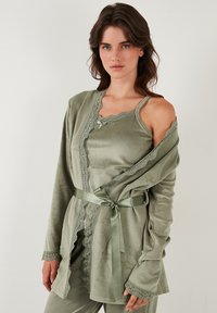 Olijfgroen loungewear-set, vervaardigd uit zachte fluwelen stof, met kantaccenten, een wikkelontwerp en een satijnen strik in de taille.