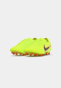 Neon gule fodboldstøvler med en glat overflade, sort Nike swoosh og pink-røde studs på sålen; indeholder snørebåndsdesign og tekstureret overdel.
