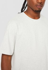 Lichtgrijs T-shirt met korte mouwen, gemaakt van zacht, textuurstof met een klassieke ronde hals. Geen zichtbare patronen of accenten.