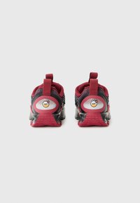 Red and black athletic shoes with a textured mesh upper, rubber sole, and two pull tabs at the heel; feature a circular branding detail.