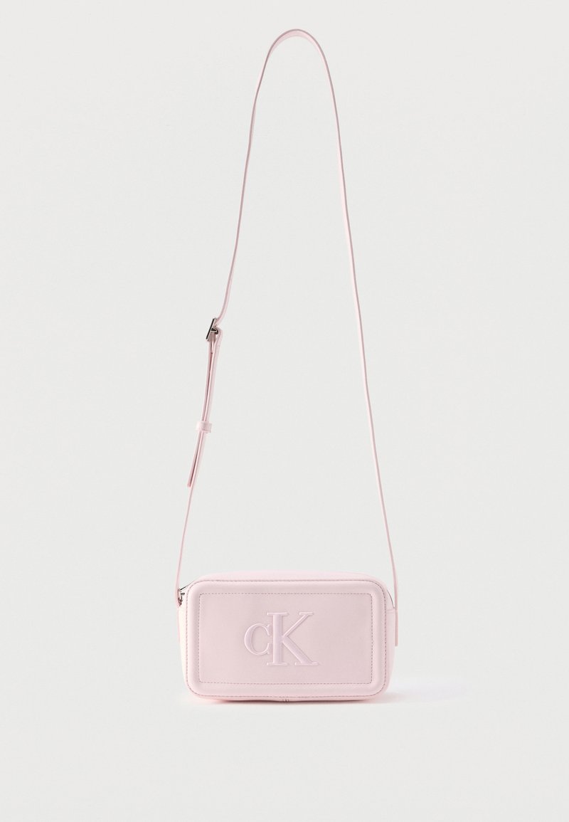 Ροζ ανοιχτό ροζ ορθογώνια τσάντα χιαστί με ρυθμιζόμενο λουράκι και ανάγλυφο λογότυπο "cK" στο εμπρόσθιο πάνελ σε λευκό φόντο.