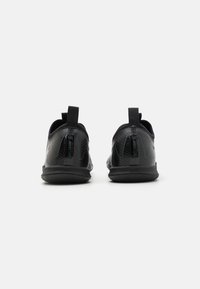 Zapatillas deportivas negras con una parte superior texturizada, dos tiradores y una suela de goma flexible. Presentan un diseño elegante y aerodinámico.
