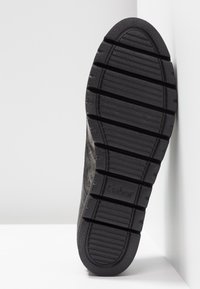 Semelle de chaussure en caoutchouc noir avec de profonds cannelures pour une meilleure adhérence, présentant une finition texturée et un logo de marque visible "Gabor" près du talon.