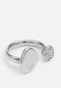 Sølvfarget ring med en glatt oval band, den ene enden har en polert overflate mens den andre er satt med små glitrende steiner.
