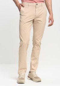 Beige chinos ar taisnu piegriezumu, izgatavoti no viegla auduma, ar pogu aizdari, sānu kabatām un diskētu logo uz kabatas.