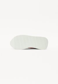 Semelle de sneaker avec une base en caoutchouc blanc texturé, présentant des rainures horizontales pour une meilleure adhérence ; possède un léger talon surélevé et un bout arrondi.