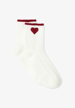 Chaussettes blanches côtelées avec une bande supérieure bordeaux et un motif en forme de cœur sur le côté extérieur. Confectionnées en matière douce, adaptées à une tenue décontractée.