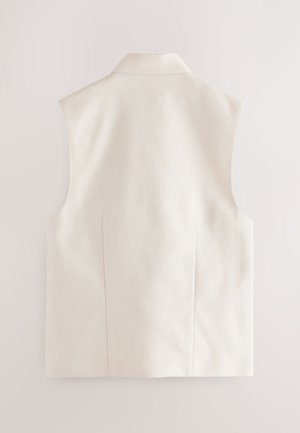 Vaaleanbeige hihaton liivi, jossa on perinteinen kaulus, istutettu leikkaus ja hienovarainen tekstuuri. Siinä on kaksi sivusaumaa eikä näkyviä kiinnikkeitä.