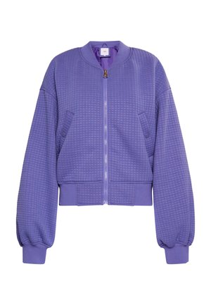 Purpura iešūtu bomberjakku ar rāvējslēdzēju priekšpusē, ribotiem piedurknēm un regulējamu apakšmalu. Iekļauj divas sānu kabatas un apaļu kakla izgriezumu.