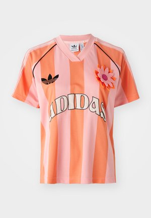 Roosa ja oranž triibuline Adidas jäänko, millel on V-kaelus, lühikesed varrukad ja lille applikaat. Esiplaanil on logo ning mustad aksendid.