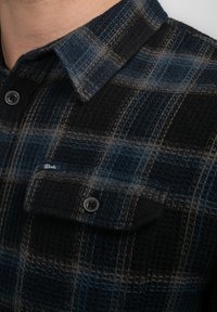 Flanellen overhemd in marineblauw en zwart ruitpatroon, met een textuurstof, een geknoopte kraag en een zak met een logo-tag.