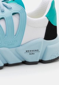 Scarpa sneaker con una tomaia bianca testurizzata, accenti turchesi e un pannello nero. Presenta una suola blu spessa con il marchio "WEEKEND MaxMara".