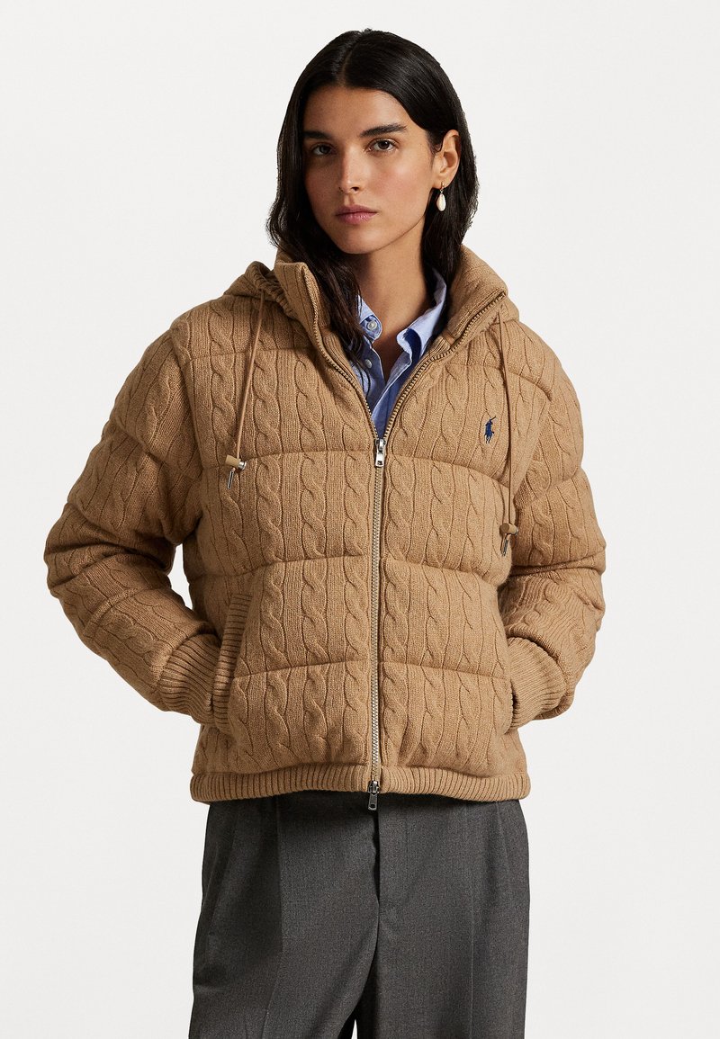 Tan kabelgebreide jas met capuchon, uitgerust met een rits aan de voorkant, geribde manchetten, zijzakken en een klein logo op de borst.