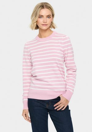 Un pull rayé rose et blanc avec un col rond et des poignets côtelés. Présente une texture douce et une coupe ajustée. Porté avec un jean foncé.