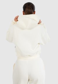 Witte hoodie met een grote capuchon, gemaakt van zacht materiaal. Beschikt over geribbelde boorden en een relaxte pasvorm, combinatie met bijpassende broek.