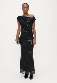 Melnas vakarkleitas ar plecus atsegto drapēto izgriezumu, ziedu fliteru rakstu, piegulošu siluetu un caurspīdīgu mežģīņu apakšu. Komplektēta ar metālisku vakarklātni.