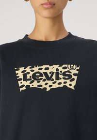 Felpa nera con un grande logo Levi's in stampa leopardata beige. Il design è completato da un collo a giro e polsini a costine. Abbigliamento casual classico.