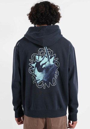 Sweat à capuche bleu marine avec un grand imprimé graphique au dos, représentant un surfeur sur un motif abstrait bleu et noir. Tissu doux, coupe décontractée.