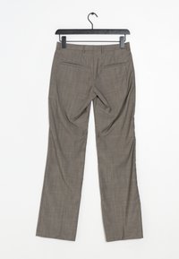 Pantaloni grigi su misura con una sottile texture. Davanti piatto, gambe dritte e due tasche posteriori. Appesi a un gancio di plastica nera.