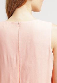 Ärmelloses rosa Kleid aus strukturiertem Stoff, mit Reißverschluss hinten und einem glatten, schlichten Design mit einem runden Ausschnitt.